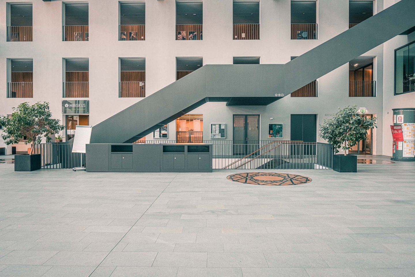 Modern courtyard with diagonal metal stairs and surrounding glass-balcony floors at the Universitaet Mozarteum building in Salzburg