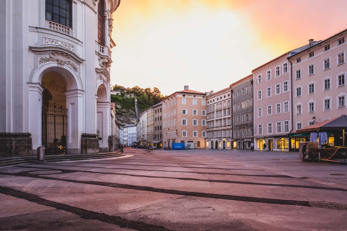 Universitatsplatz square with the curved apse of Kollegienkirche at sunset in Salzburg old town.