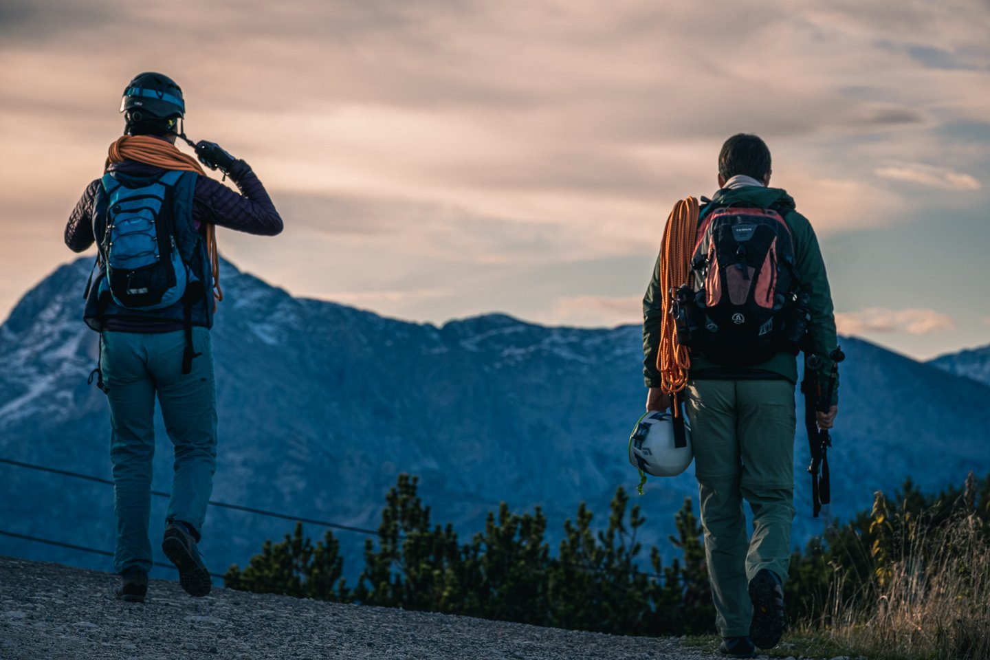 Two climbers with ropes and helmets walk along the Untersberg summit plateau at dawn.