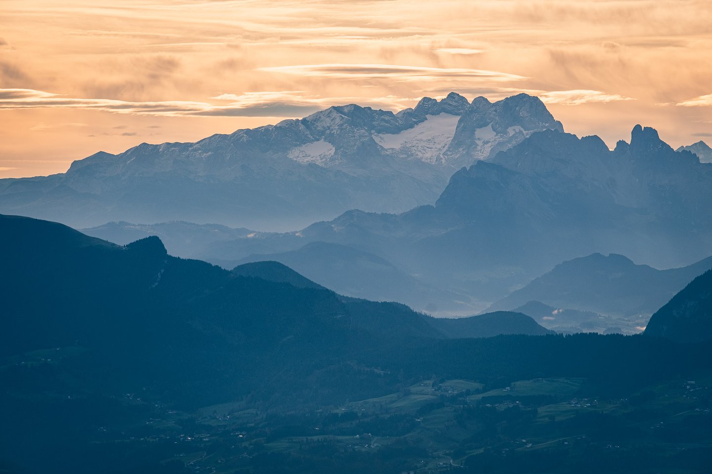 Ridges of the Hoher Goell massif rise above misty valleys at sunrise from the Untersberg in Salzburg.