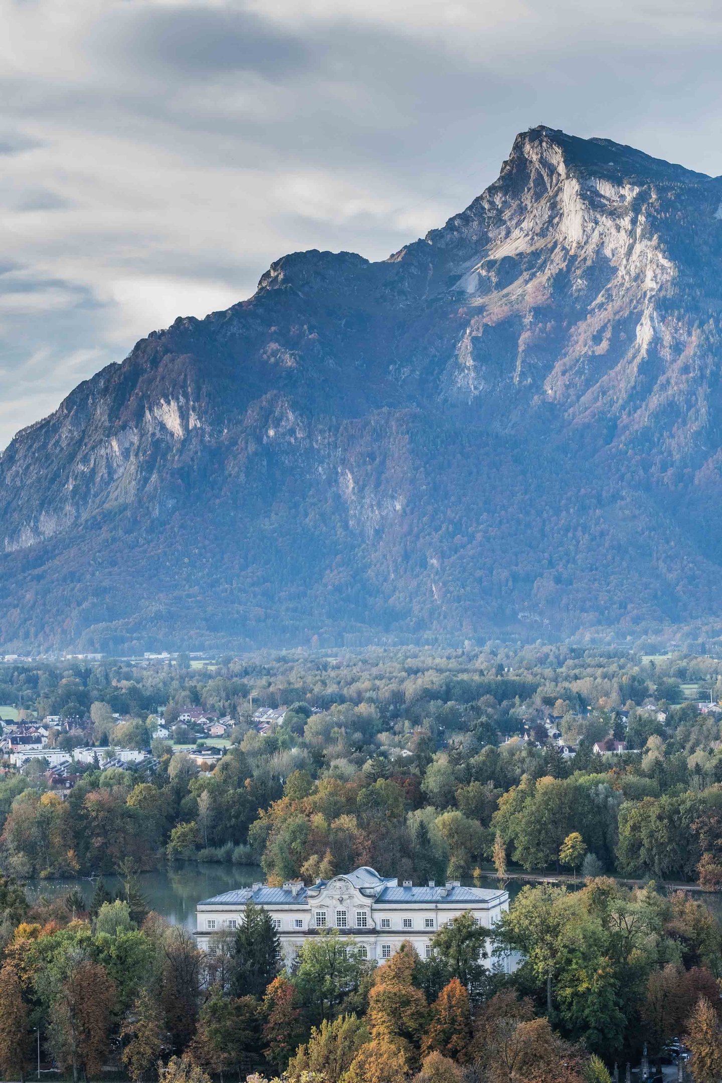 Untersberg mountain towering over Schloss Leopoldskron and its pond on an autumn morning in Salzburg.