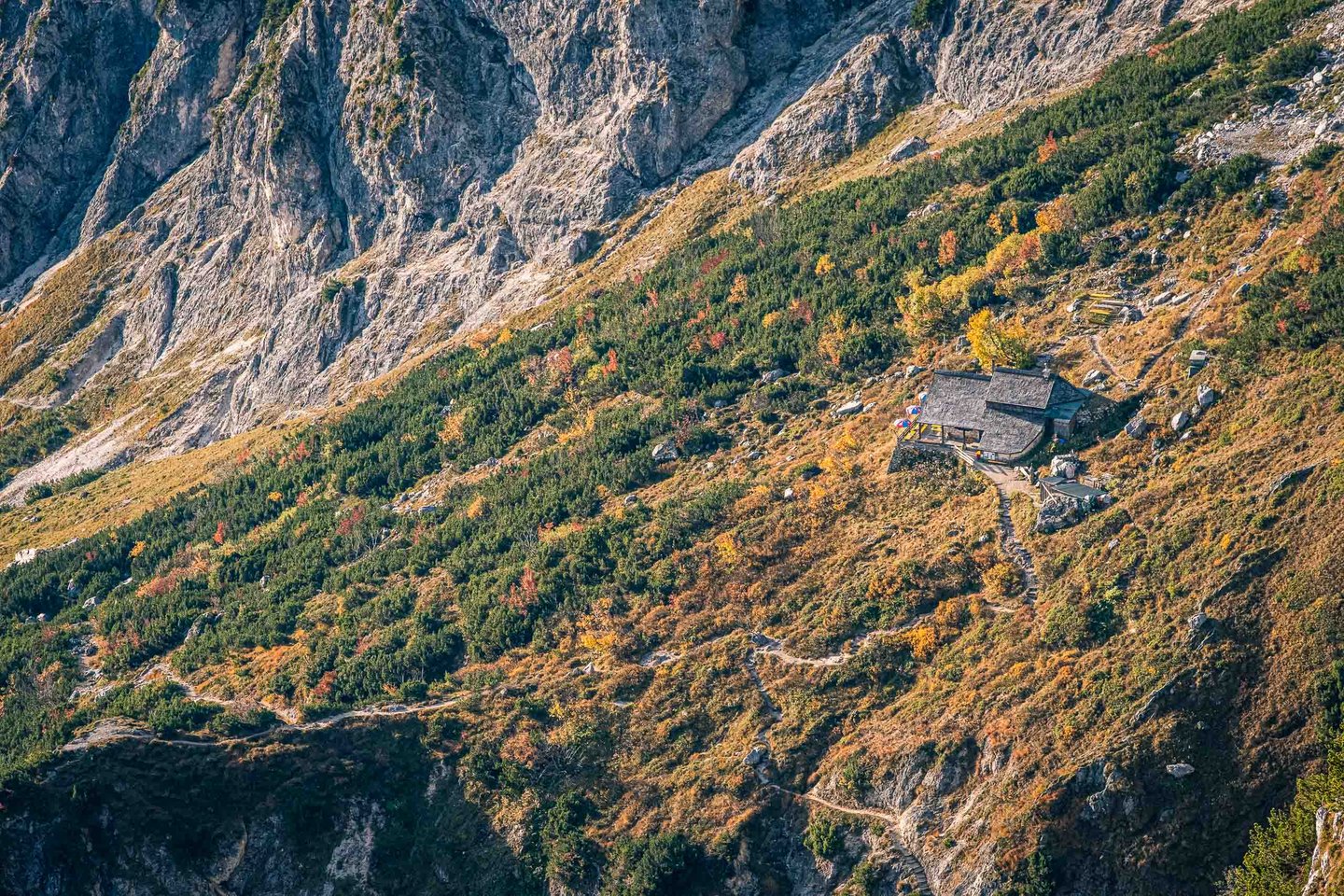 Alpine hut perched on an autumn-colored slope beneath steep cliffs on the Untersberg in Berchtesgaden.