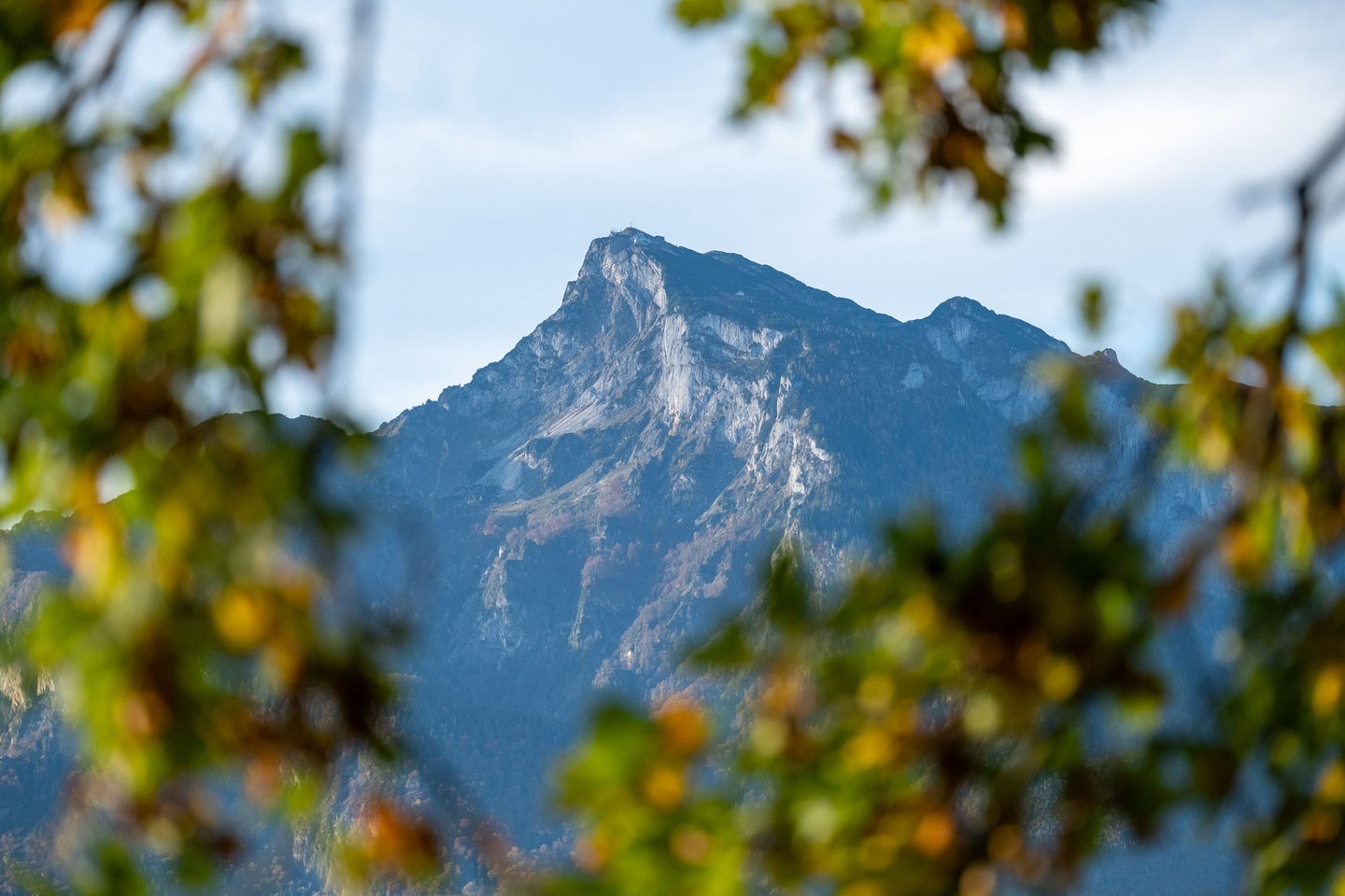 Untersberg rocky summit framed by autumn leaves from a distant vantage near Salzburg.