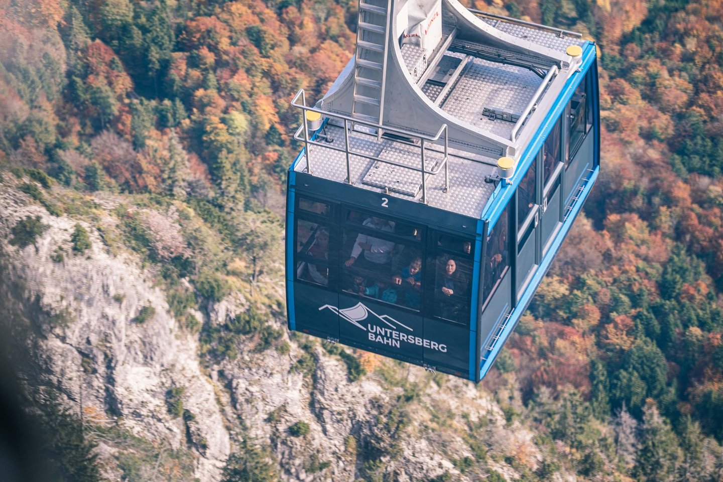 Blue Untersbergbahn cable car cabin above autumn forest between Grodig and Untersberg summit