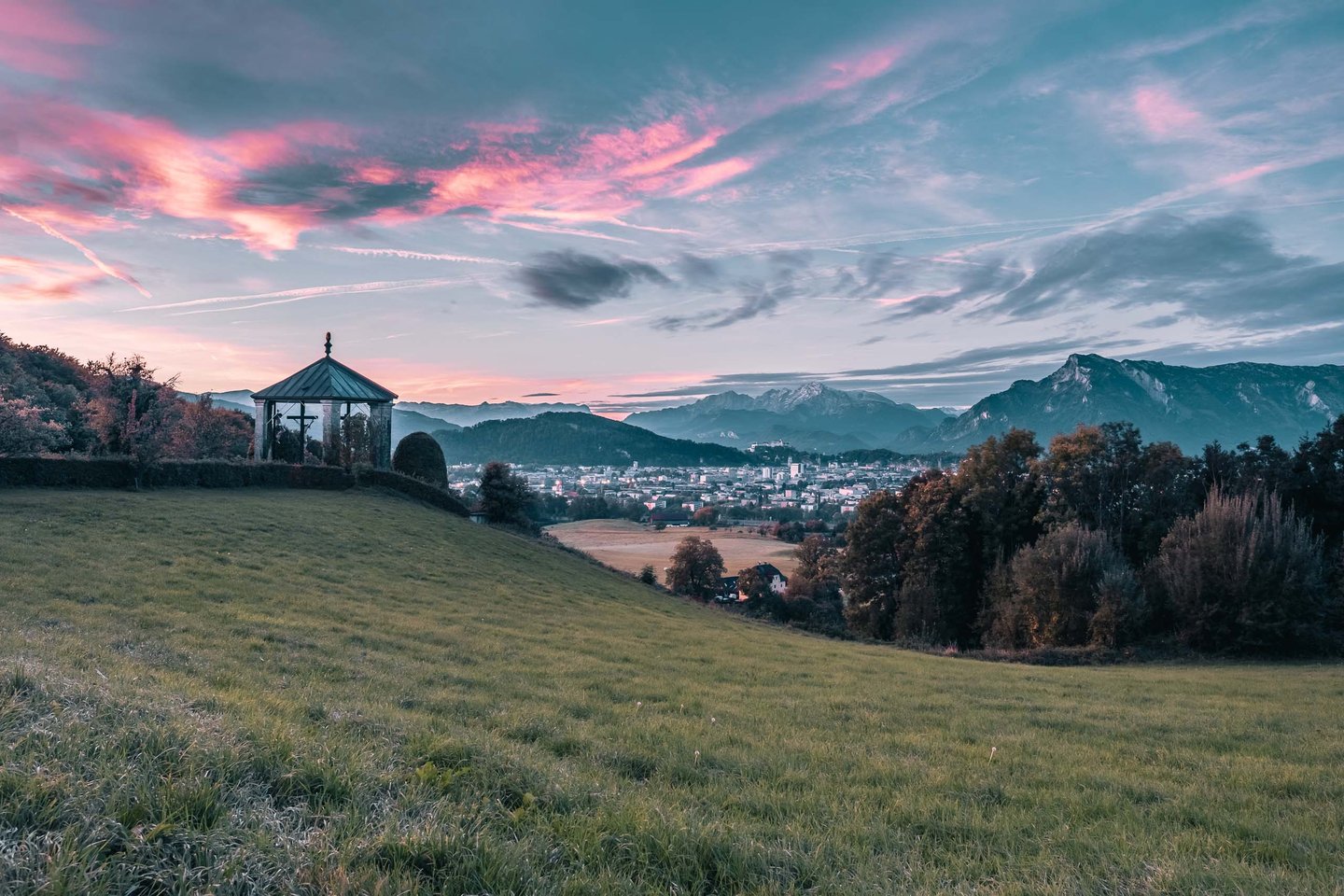 Open pavilion on Maria Plain meadow at sunrise with the Alps behind near Salzburg.