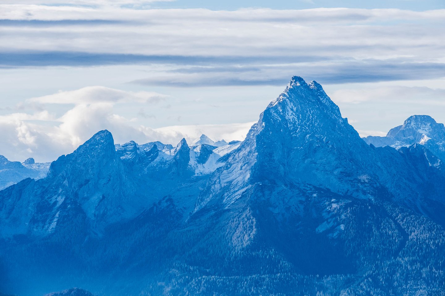 Sharp Watzmann summit glows against layered cloud above shadowed Berchtesgaden ridges.