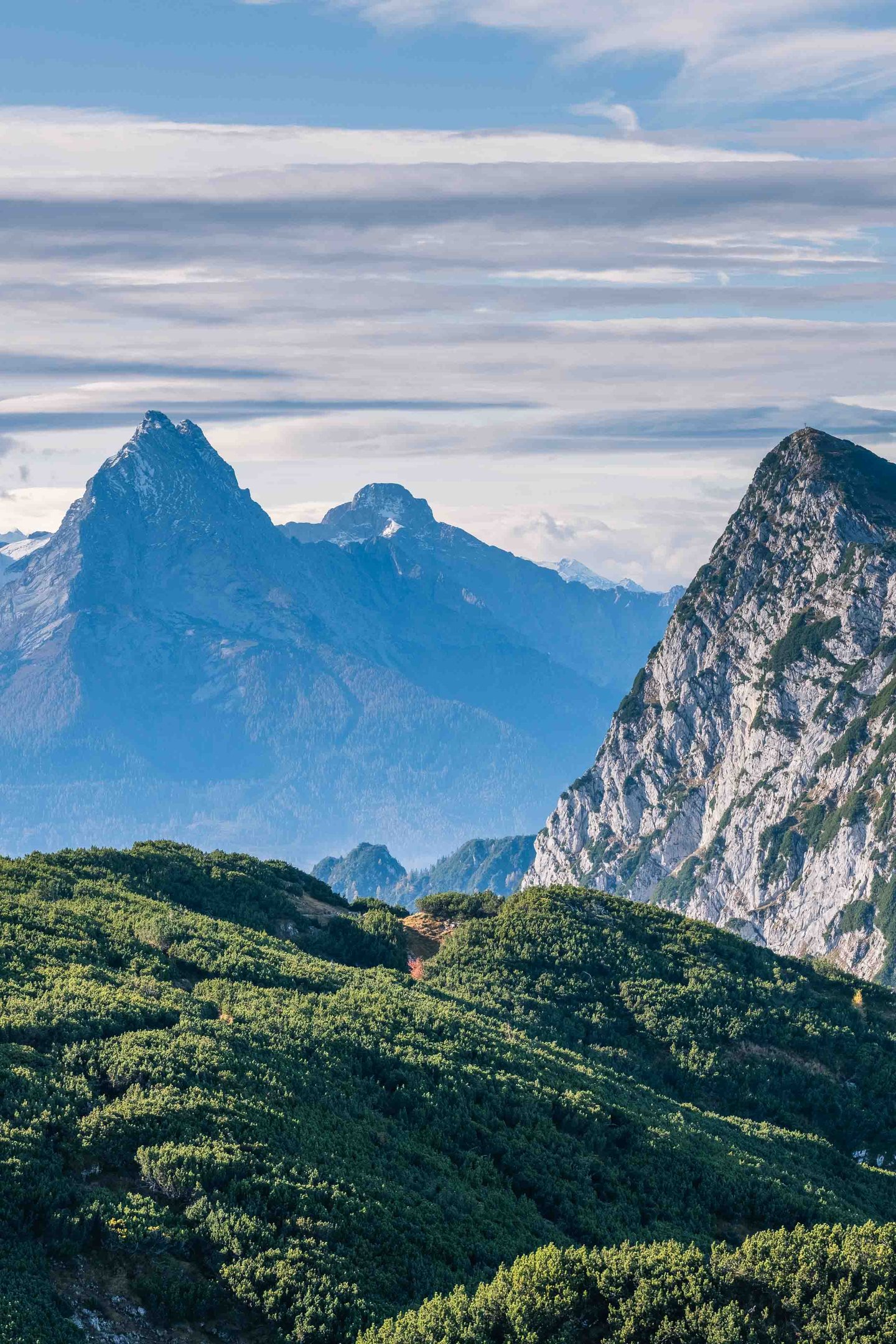The Watzmann and Hochkalter peaks rise above forested ridges seen from the Untersberg in Berchtesgaden.
