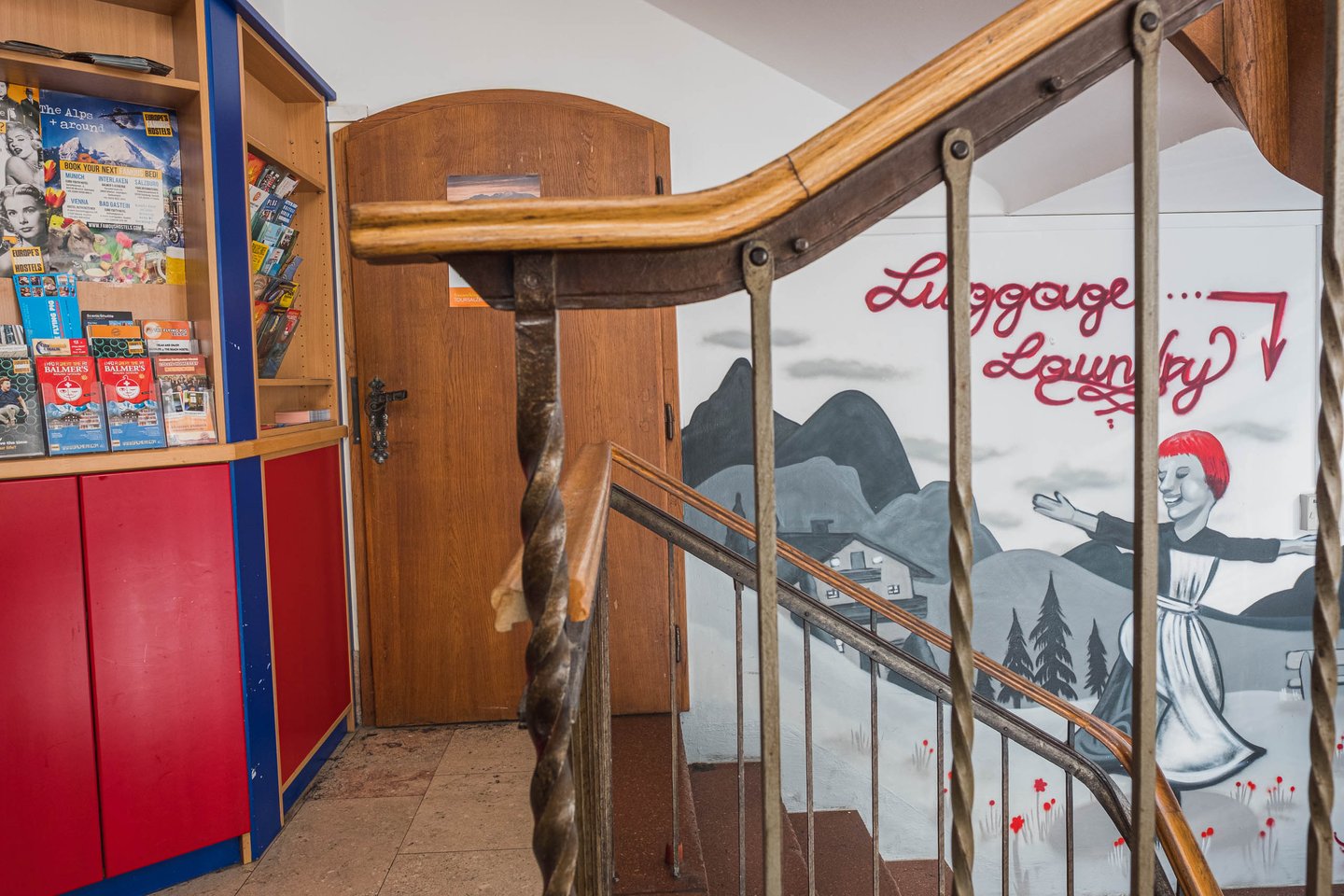 Wooden staircase and Luggage Lounge mural with Sound of Music theme inside YoHo Hostel in Salzburg