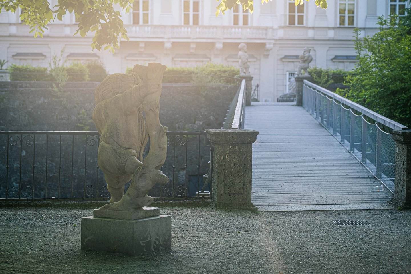 Stone dwarf statue beside a footbridge at Mirabell Gardens in Salzburg.