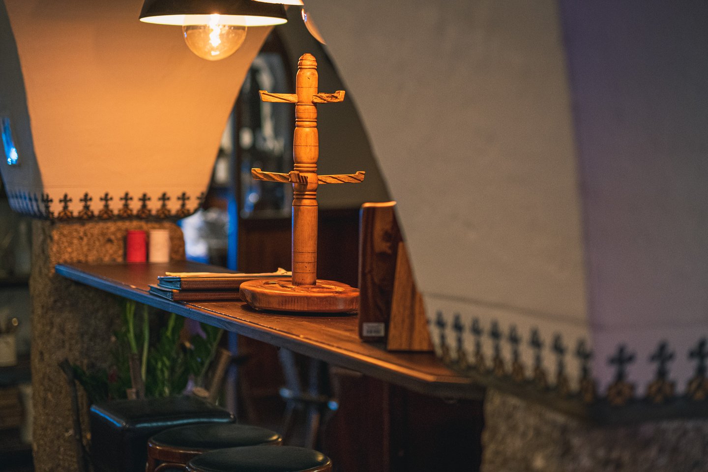 A tall turned wooden pretzel stand rises from the narrow standing counter of Zwettler's Wirtshaus in Salzburg, lit by a bare bulb hung under the vault.