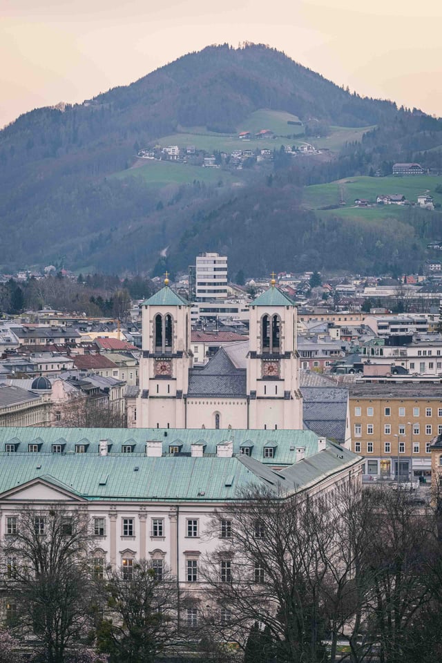 Twin-towered Andraekirche with Gaisberg mountain rising above Salzburg Neustadt.