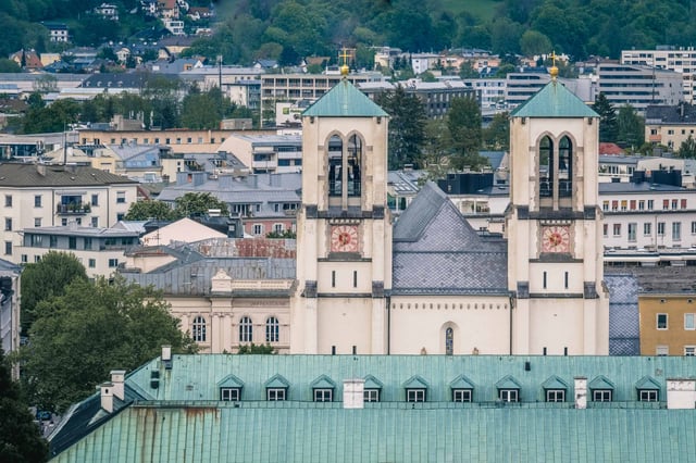 Andrakirche twin Gothic revival towers with red clocks rising above Mirabell roof in Salzburg.