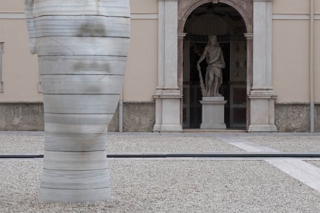 Awilda head sculpture by Jaume Plensa foregrounds a baroque Neptune fountain in Salzburg old town.