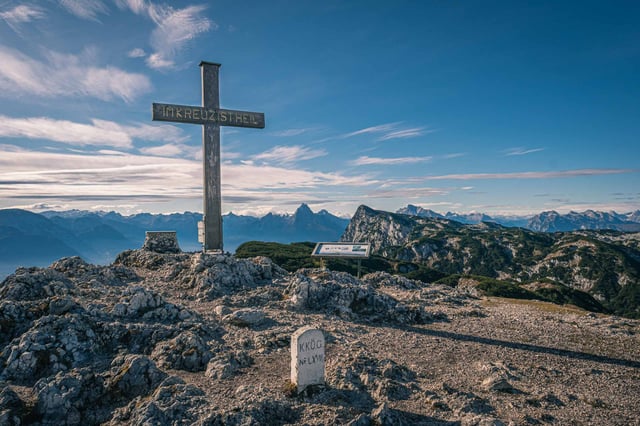 Summit cross with Im Kreuz ist Heil inscription at Berchtesgadener Hochthron with Alps behind