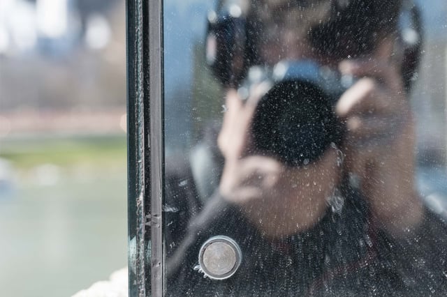 Photographer self-portrait reflected in the Beyond Recall glass artwork on the Staatsbruecke in Salzburg