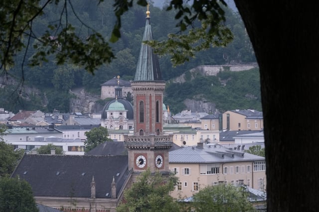 Christuskirche red brick clock tower rising above old town rooftops in Salzburg