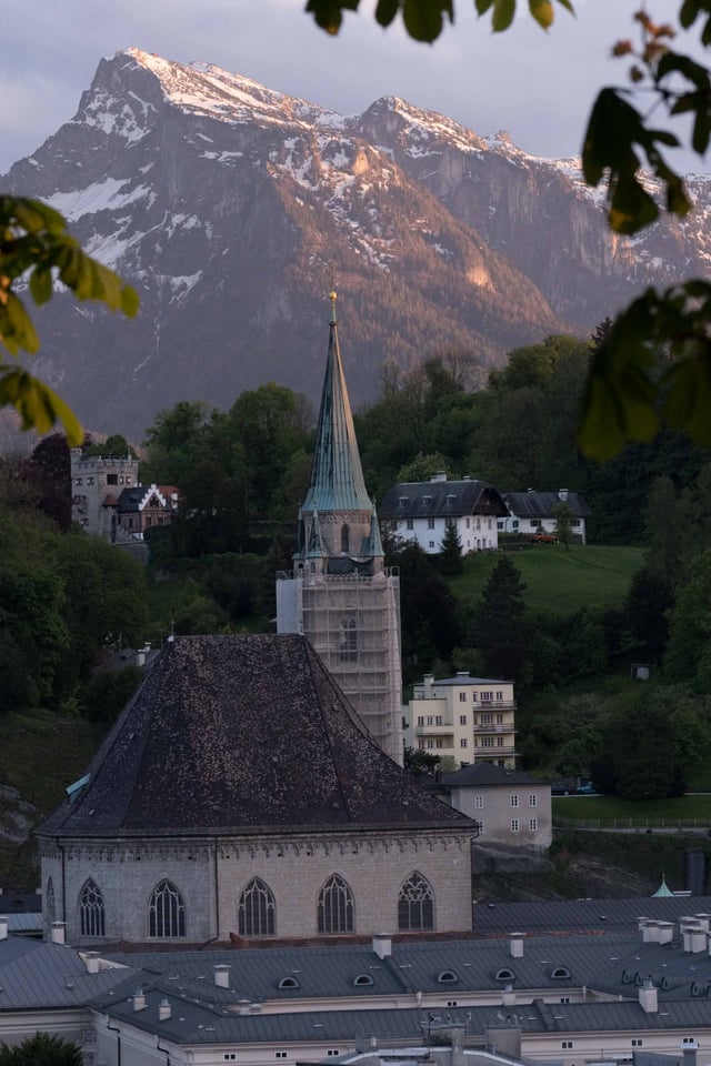 Christuskirche Gothic revival church tower with snow streaked Untersberg behind in Salzburg.