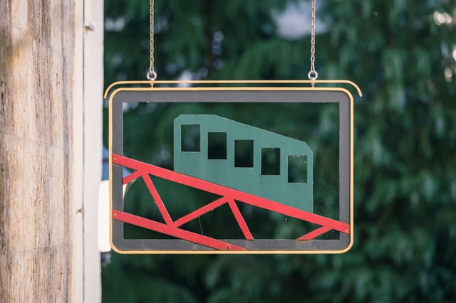 Festungsbahn funicular sign with green carriage and red rails in Salzburg old town.