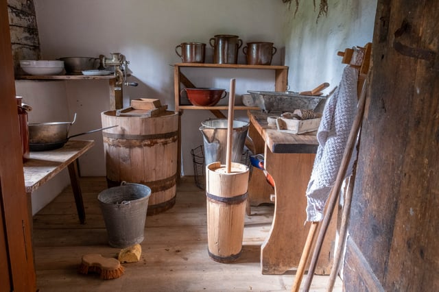 Wooden butter churn and copper milk pots in a traditional farm workroom at an open-air museum near Salzburg.