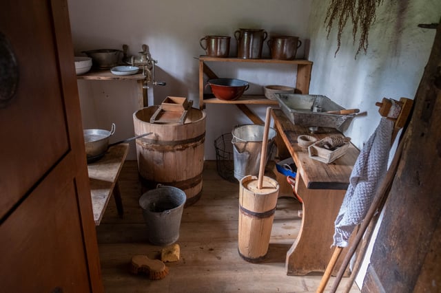 Traditional dairy workroom with wooden butter churns and copper pots at an open-air museum near Salzburg.