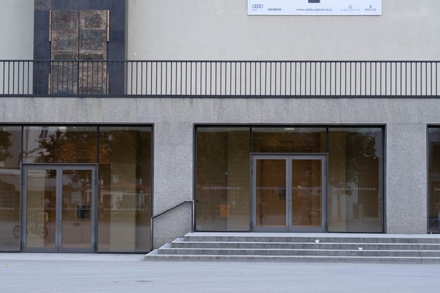 Glass entrance doors of the Grosses Festspielhaus with Salzburger Festspiele lettering in Salzburg old town.
