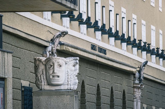 Theater mask sculpture on a pillar in front of the Festspielhaus facade on Hofstallgasse in Salzburg