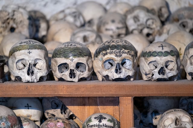 Four of the oldest skulls in the charnel house sit in a row, their crowns painted with broad green laurel bands, one dated 1780 and another inscribed Gob ihr Gott die ewige Ruhe.