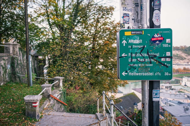 Trail sign pointing to Altstadt Franziskischlossl and Hettwer Bastei on Kapuzinerberg in Salzburg