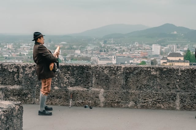 Traditional Prangerschuetzen marksman in lederhosen loads a handgonne on the fortress rampart in Salzburg