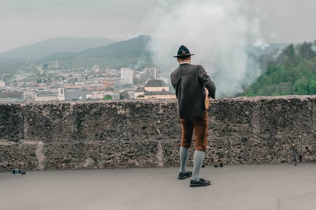 Prangerschuetzen marksman in lederhosen fires a ceremonial handgonne from the fortress rampart in Salzburg