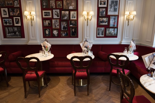 Red banquette seating below festival portrait photographs inside Hotel Sacher Salzburg