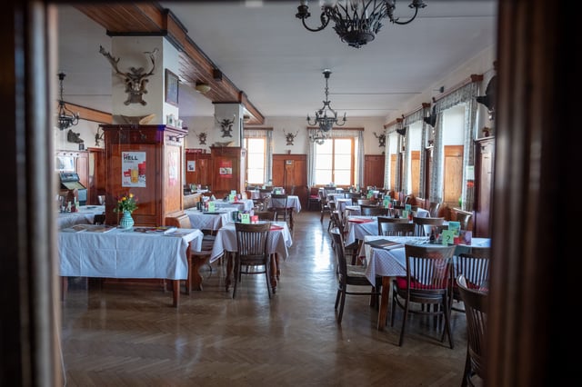 Seen through a glass door, the Kaisersaal dining room of the summit hotel stands empty with its herringbone parquet, white-clothed tables, wrought iron chandeliers and antler trophies on the panelled walls.