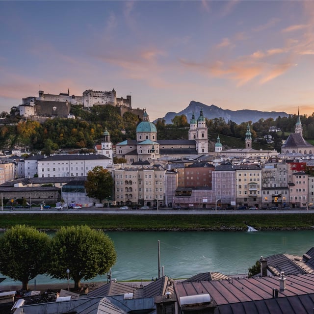 Panorama of Hohensalzburg Fortress and Altstadt skyline above the Salzach at sunset in Salzburg.