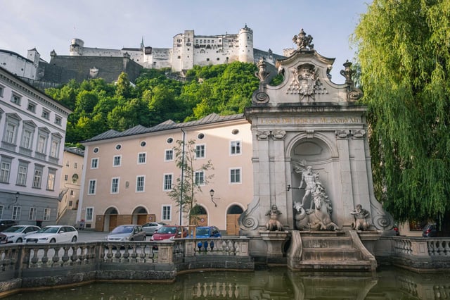 Kapitelschwemme fountain with Triton sculpture below Hohensalzburg fortress in Salzburg old town