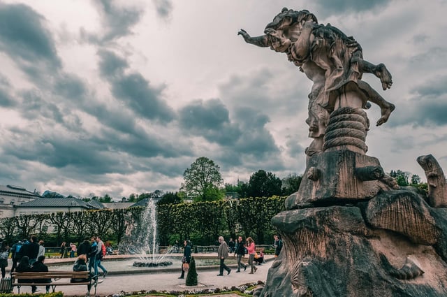 Pegasus fountain and baroque statue in Mirabell Gardens with Mirabell Palace behind in Salzburg