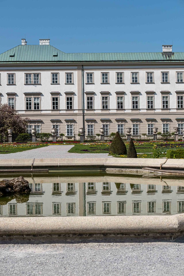 Mirabell Palace mirrored in the Pegasus fountain pond at Mirabell Gardens in Salzburg.