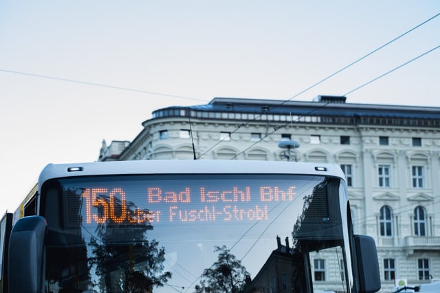Postbus destination display reading Bad Ischl in front of the Mozarteum facade at Mirabellplatz in Salzburg.