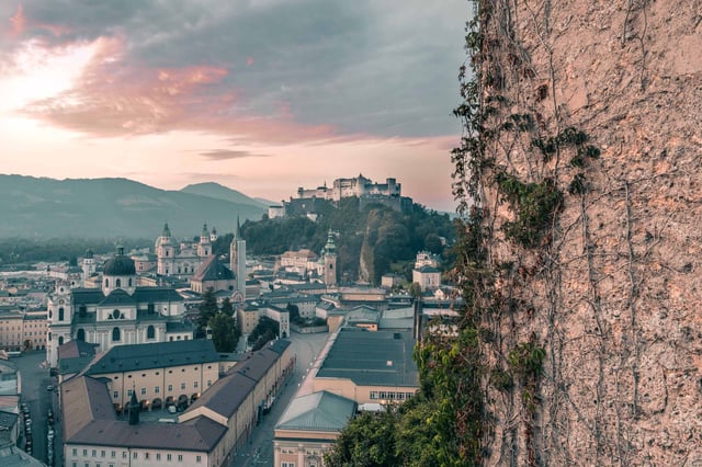 Altstadt skyline with fortress framed by ivy wall from Monchsberg lookout in Salzburg