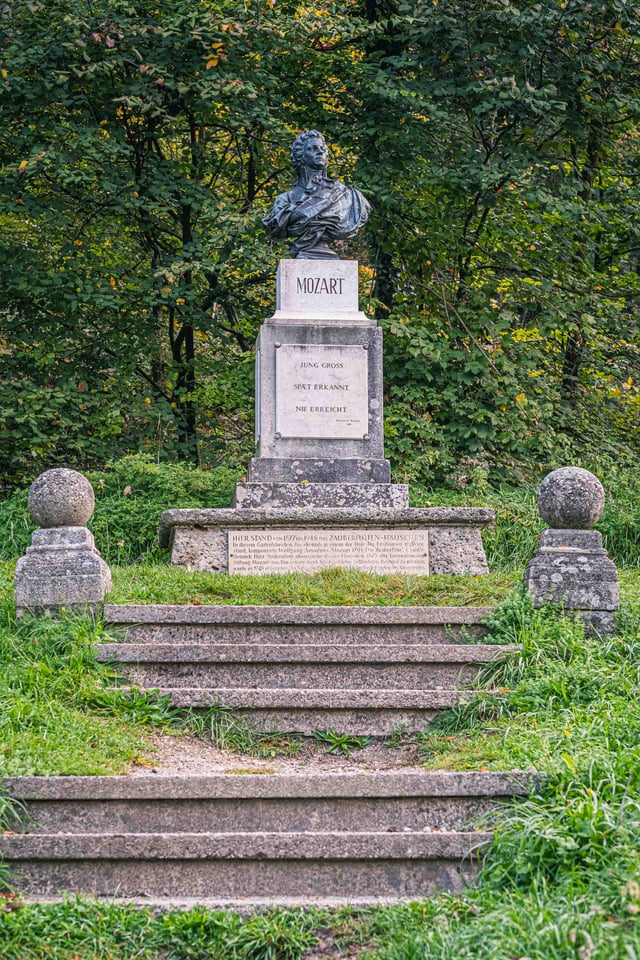 Mozart memorial bust on stone pedestal with steps in the forest on Kapuzinerberg in Salzburg.