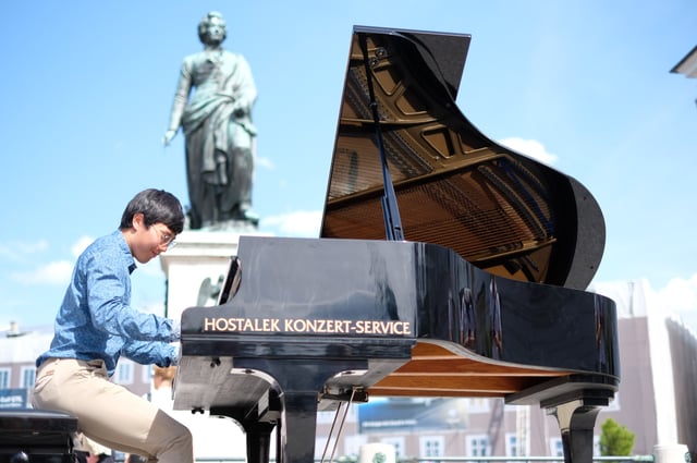Pianist plays a grand piano below the Mozart statue on Mozartplatz in Salzburg old town