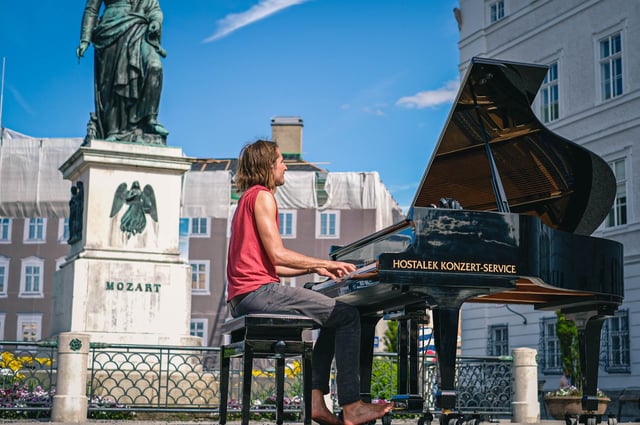 Barefoot pianist performs on a grand piano beside the Mozart monument on Mozartplatz in Salzburg