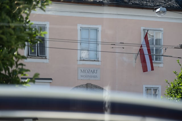 Pink facade of Mozart Wohnhaus with Austrian flag in Salzburg old town.