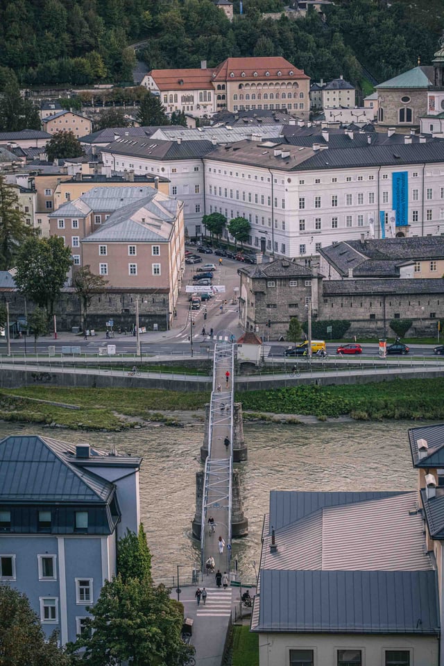 Mozartsteg footbridge crossing the Salzach with pedestrians seen from above on Kapuzinerberg in Salzburg