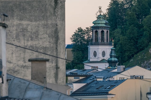 Glockenspiel tower of the Neue Residenz with arched belfry lantern rising above Salzburg Altstadt rooftops at dusk