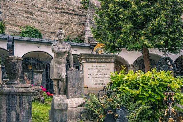 Petersfriedhof cemetery with arcaded crypts statue and ornate tombstones in Salzburg old town