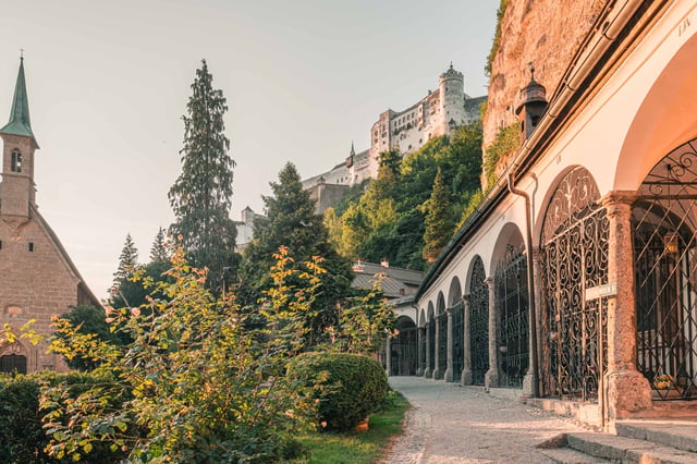 Arcade crypts of St Peter cemetery with Hohensalzburg Fortress rising on the cliff above in Salzburg.