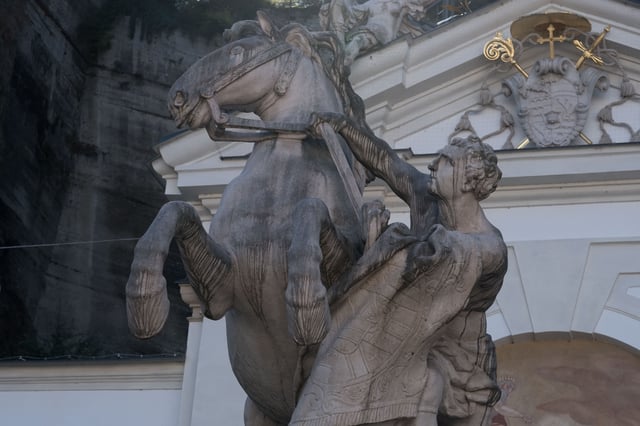 Pferdeschwemme rearing horse and tamer statue with coat of arms above in Salzburg