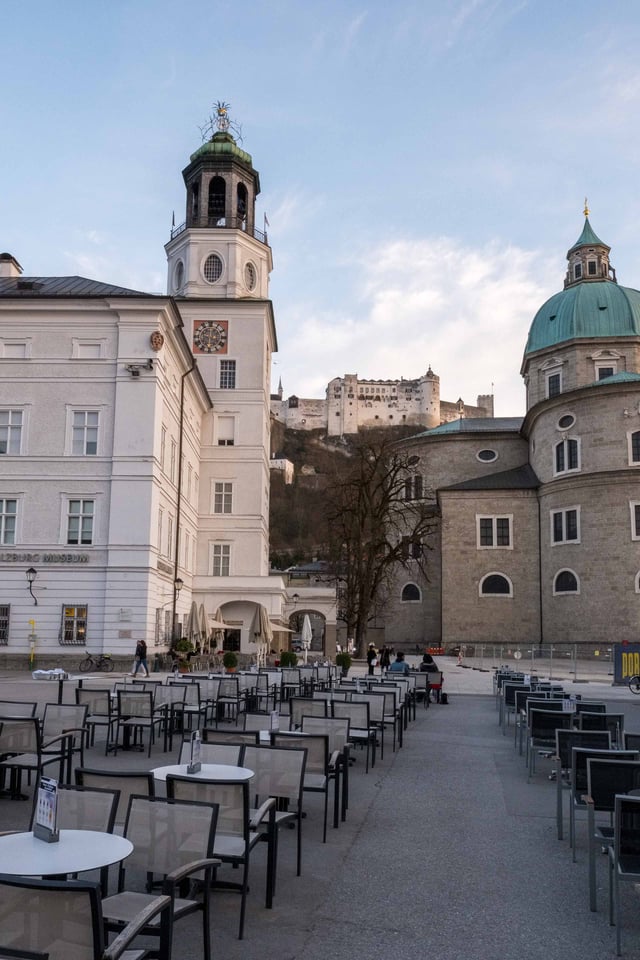Residenzplatz with Glockenspiel tower Dom dome and Hohensalzburg Fortress above in Salzburg old town.