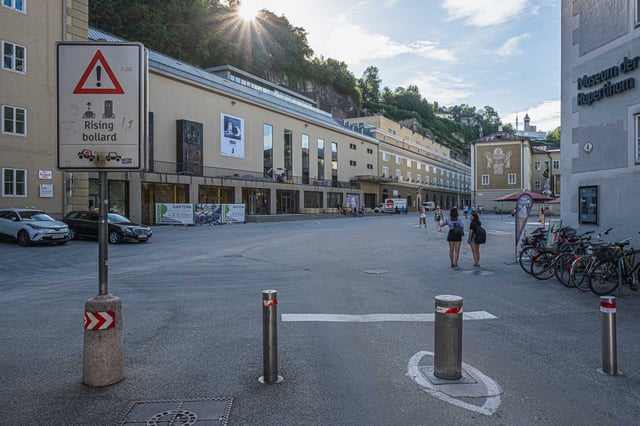 Museum der Moderne Rupertinum sign at Festspielbezirk plaza with Moenchsberg cliff in Salzburg.