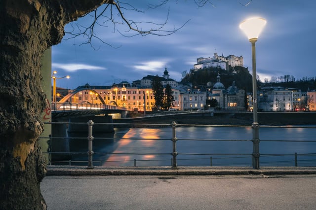 Salzach River at blue hour with Hohensalzburg Fortress illuminated above the old town.